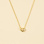 Load image into Gallery viewer, Gold heart-shaped pendant necklace on a beige background
