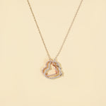 Load image into Gallery viewer, A clean product shot of a two-tone interlocking hearts necklace on a neutral cream background. The image clearly displays the intricate silver and rose gold pavé crystal hearts, a beautiful symbol of love and connection.
