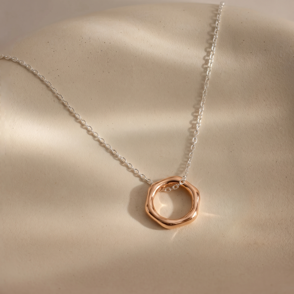 Necklace with a rose gold pendant on a beige surface