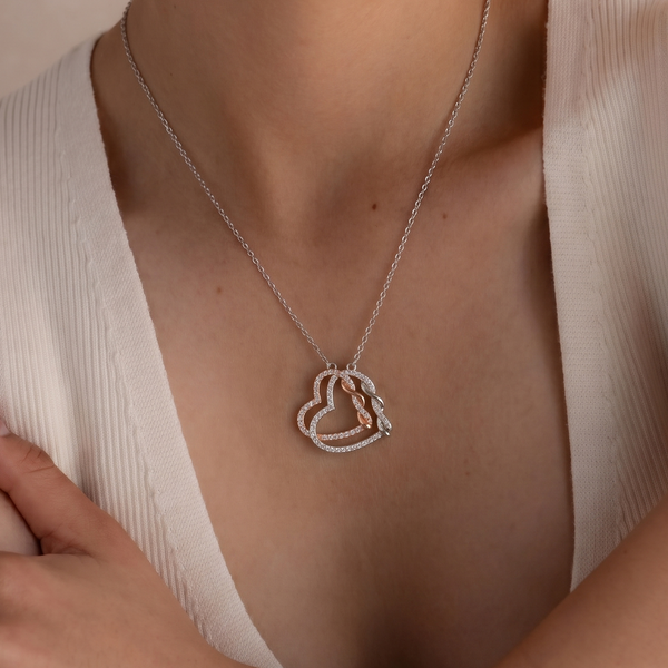 Necklace with a round pendant worn by a person in a beige top.