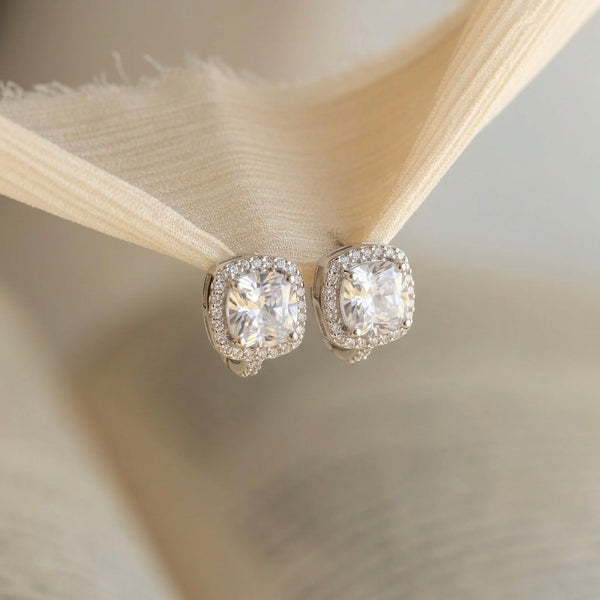 Pair of diamond earrings on a soft fabric background