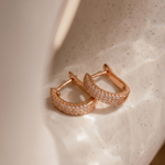 Load image into Gallery viewer, Rose gold hoop earrings with diamond accents on a textured beige surface
