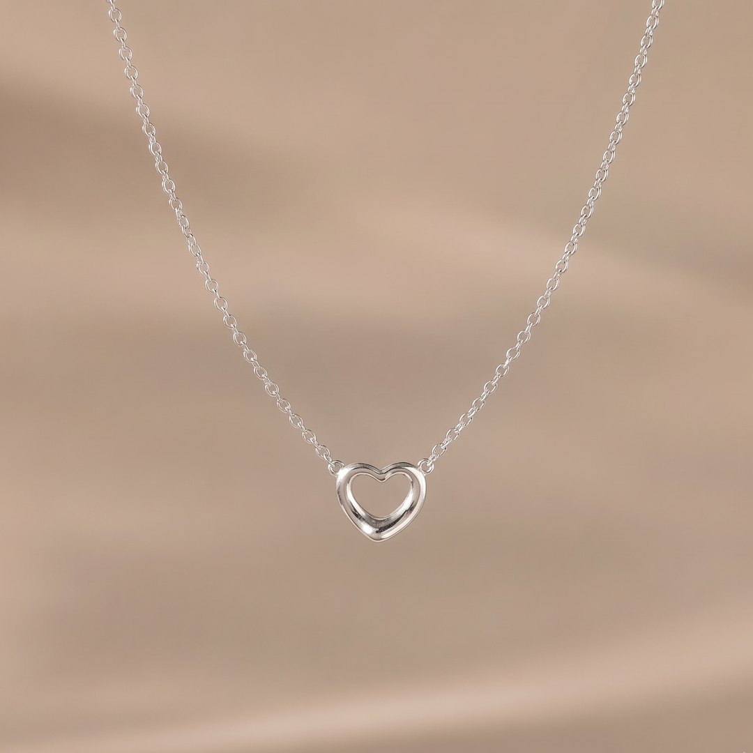 Silver heart-shaped necklace on a beige background
