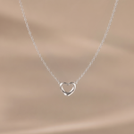Load image into Gallery viewer, Silver heart-shaped necklace on a beige background
