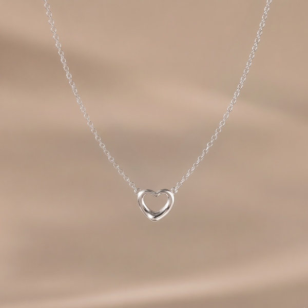 Silver heart-shaped necklace on a beige background