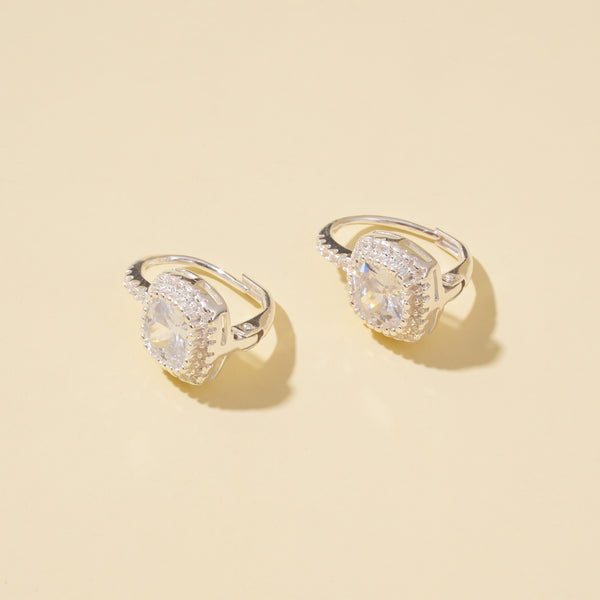 Two silver earrings with large gemstones on a beige background