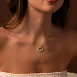 Load image into Gallery viewer, Woman wearing a gold necklace with a pearl pendant against a brown background
