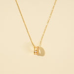Load image into Gallery viewer, A clean, minimalist product shot of a gold honeycomb necklace on a neutral cream background. The image clearly displays the intricate barrel pendant, which features white mother-of-pearl hexagonal inlays bordered by a band of sparkling pavé crystals.
