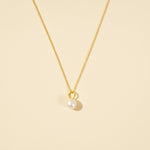 Load image into Gallery viewer, A clean, minimalist product shot of a gold pearl necklace on a neutral cream background. The image clearly displays the pearl necklace with cable chain.
