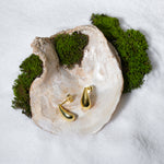 Load image into Gallery viewer, A luxurious product shot of minimalist gold teardrop stud earrings from Zewory Jewellery. The pair of elegant, polished droplet studs are artistically displayed inside a large seashell on a bed of white sand and moss.
