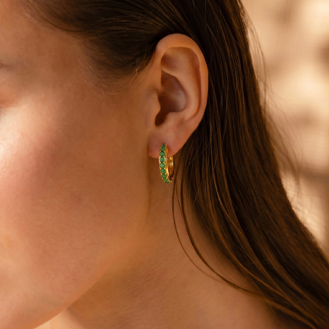 green gemstone stud earrings on women ear