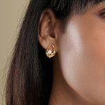 Load image into Gallery viewer, A close-up of a model wearing a modern gold and pearl stud earring from Zewory Jewellery. The abstract, open-loop design with a central pearl sits elegantly on her earlobe, making it a perfect accessory for everyday wear.
