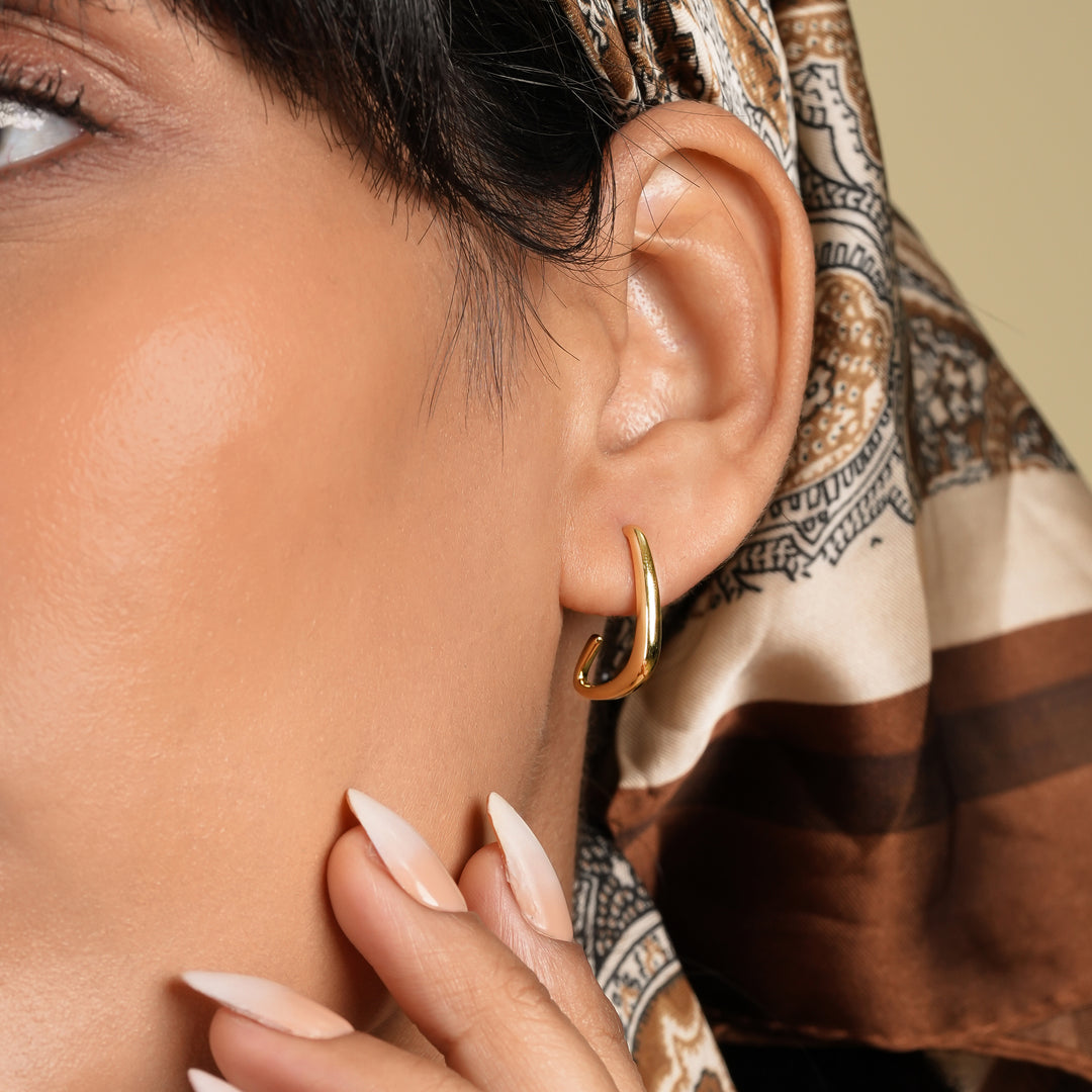 Close-up of a woman wearing a gold hoop earring with a patterned headscarf.
