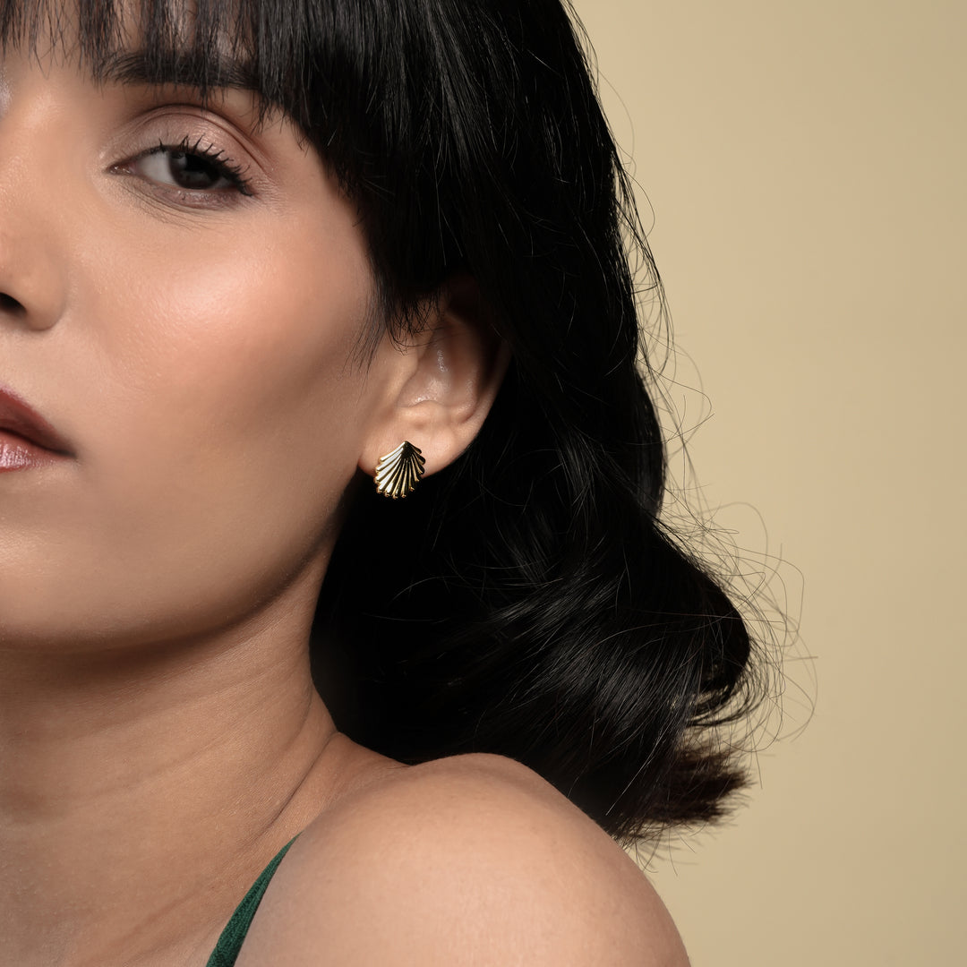 Close-up of a woman wearing gold earrings with a beige background