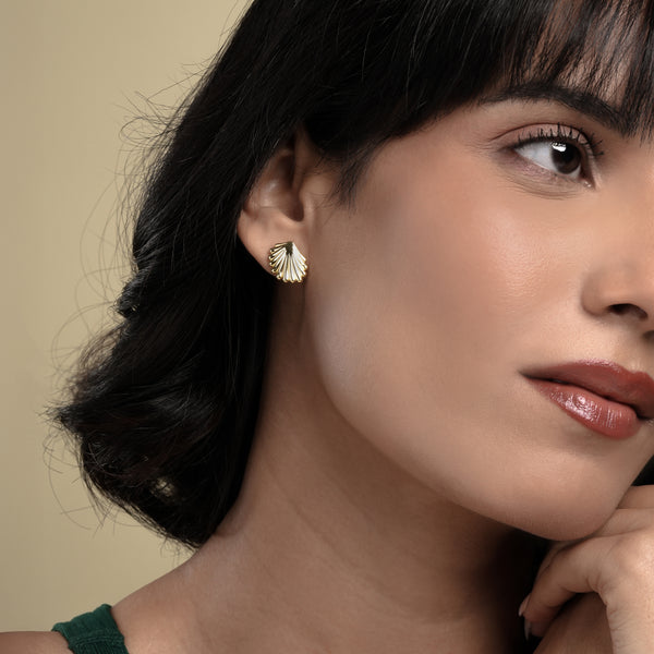 A close-up of a model wearing a delicate gold seashell stud earring from Zewory Jewellery. The detailed, ribbed scallop shell design sits elegantly on her earlobe, showcasing a chic, ocean-inspired accessory.