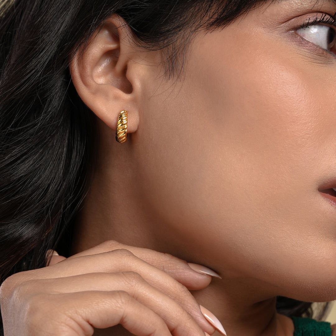 Close-up of a woman wearing a gold hoop earring with a blurred background