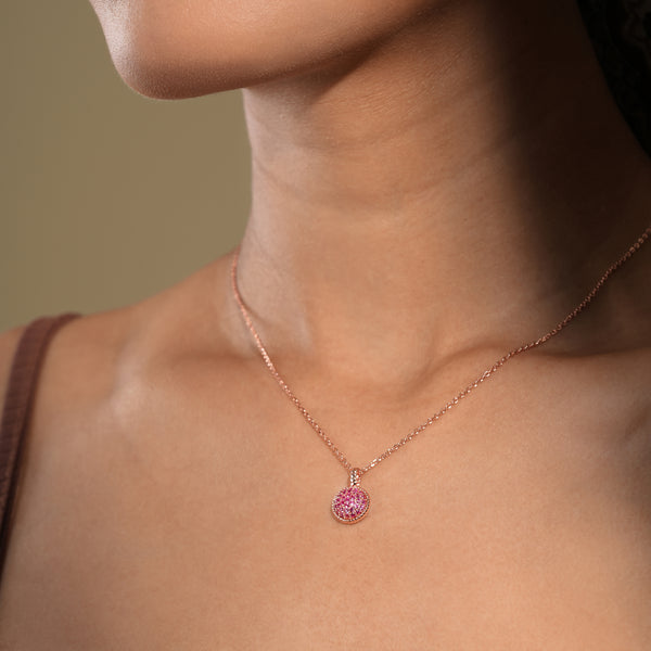 Necklace with a pink pendant worn by a person against a neutral background