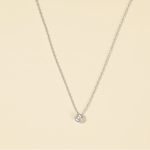 Load image into Gallery viewer, Delicate silver necklace with a small round pendant on a beige background
