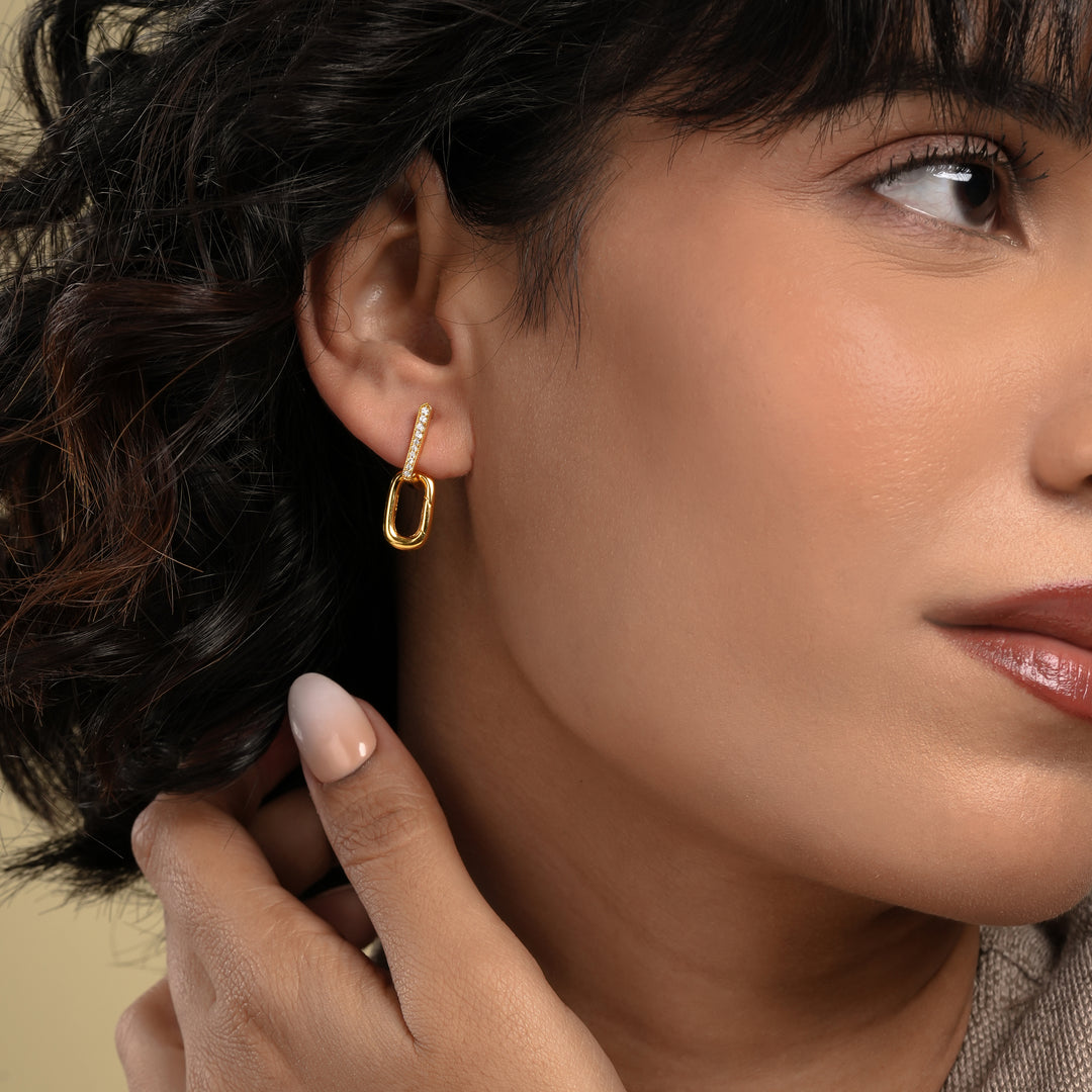 Close-up of a woman wearing a gold hoop earring with a neutral background